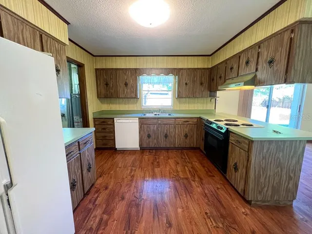 a kitchen with stainless steel appliances granite countertop wooden floors and sink
