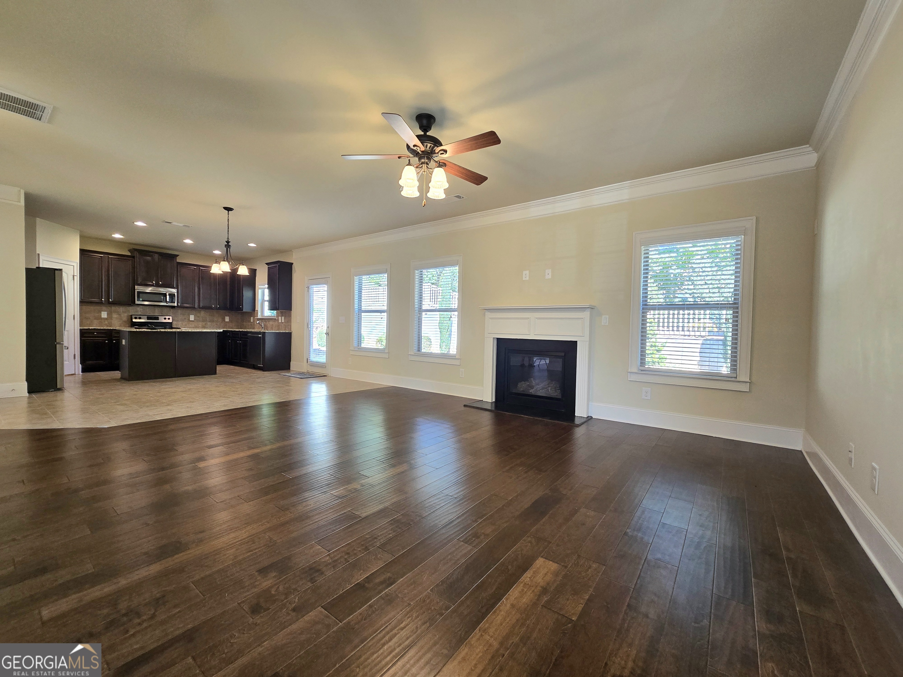 9 Ravine Drive Newnan, GA 30265 - Photo 9 of 46 an empty room with wooden floor fireplace and a kitchen view