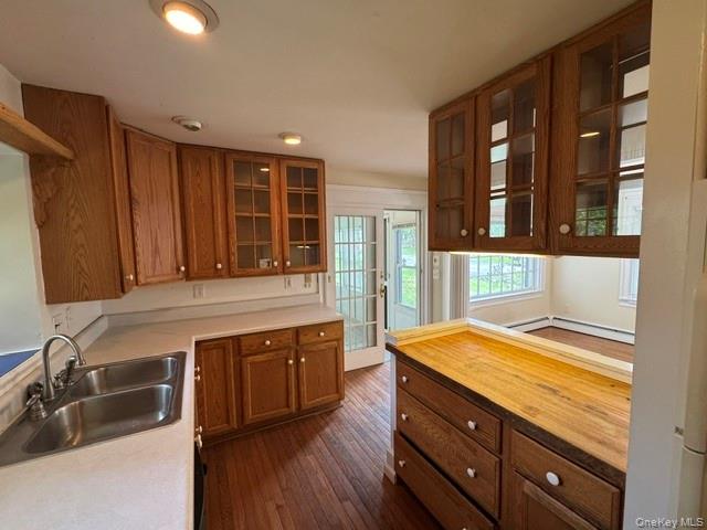 74 South Airmont Road Suffern, NY 10901 - Photo 15 of 42 Kitchen featuring wood cabinetry, some with glass-front doors, a double basin stainless steel sink, light-toned countertops, and wood-finish flooring