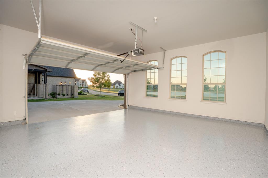 1316 Limestone Ridge Road Mansfield, TX 76063 - Photo 32 of 40 Spacious garage featuring a light-toned epoxy-coated floor, automatic overhead door, and three arched windows