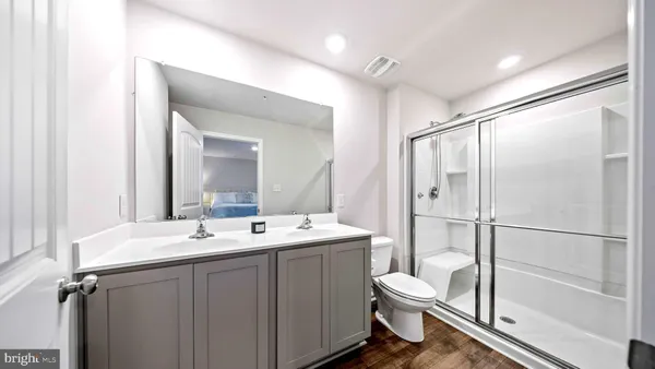 a bathroom with a double vanity sink toilet mirror and shower