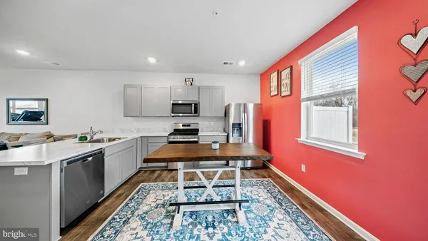 a kitchen with stainless steel appliances granite countertop a stove a sink dishwasher and a refrigerator with wooden floor