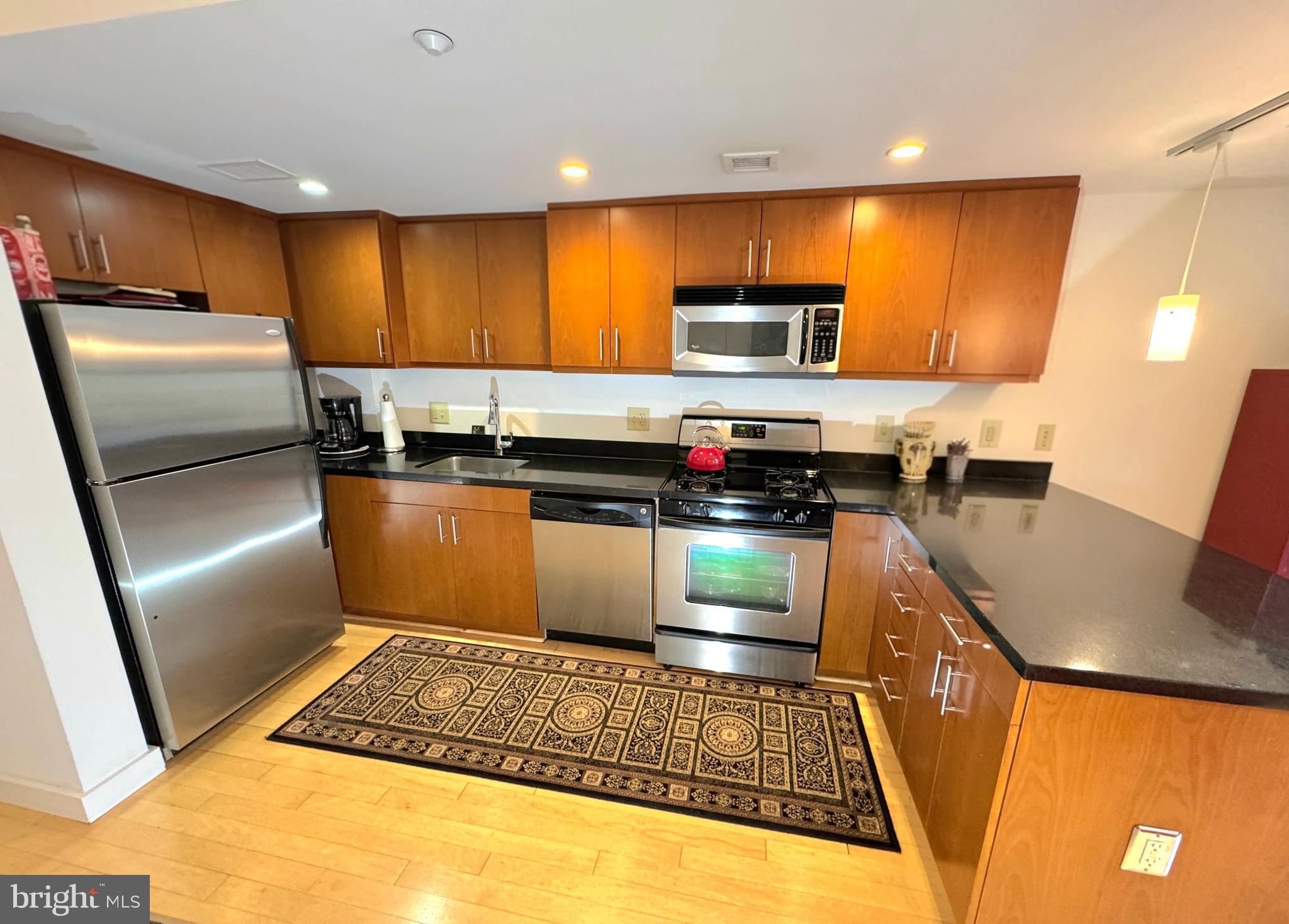 912 F Street Northwest, Unit 703 Washington, DC 20004 - Photo 16 of 56 a kitchen with stainless steel appliances granite countertop a refrigerator stove top oven a sink and dishwasher