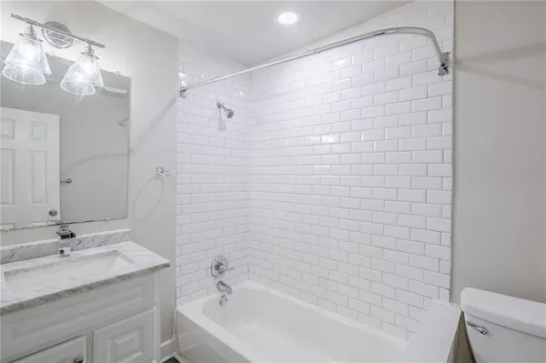 a bathroom with a granite countertop sink a toilet and shower