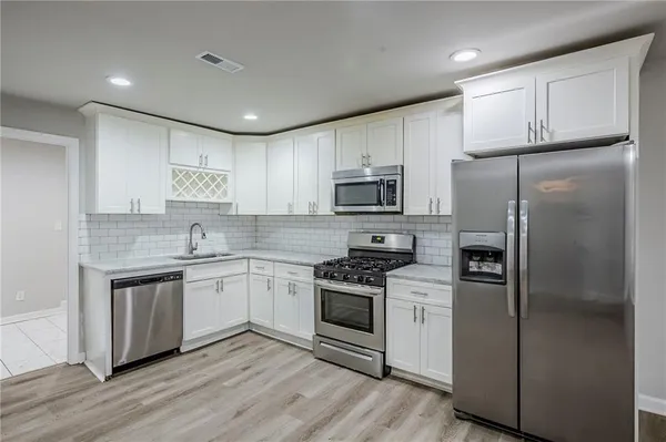 a kitchen with white cabinets stainless steel appliances and a refrigerator