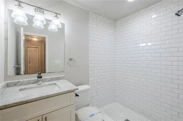 a bathroom with a granite countertop sink a toilet and mirror