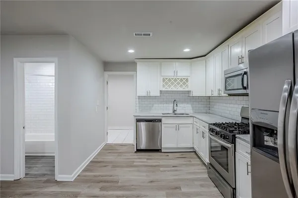 a kitchen with stainless steel appliances granite countertop a stove top oven a sink and a refrigerator