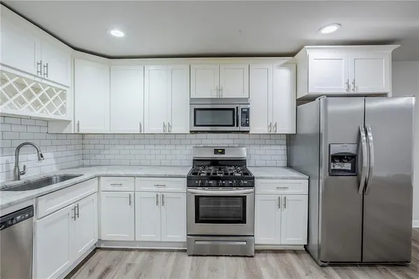 a kitchen with white cabinets sink and stainless steel appliances