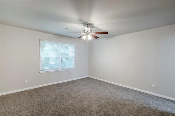 an empty room with a window and a fan