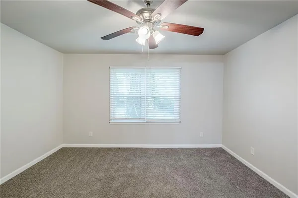 an empty room with a chandelier fan and windows