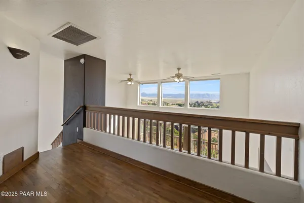an empty room with wooden floor fan and windows