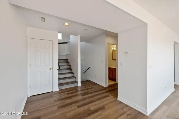 an empty room with wooden floor ceiling fan and windows
