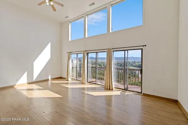 an empty room with wooden floor fireplace and windows