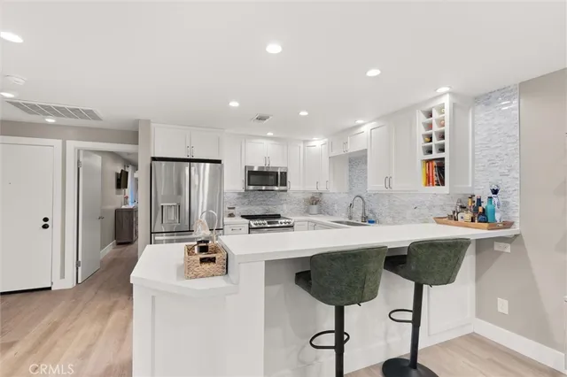 a kitchen with stainless steel appliances a sink a stove a refrigerator and cabinets