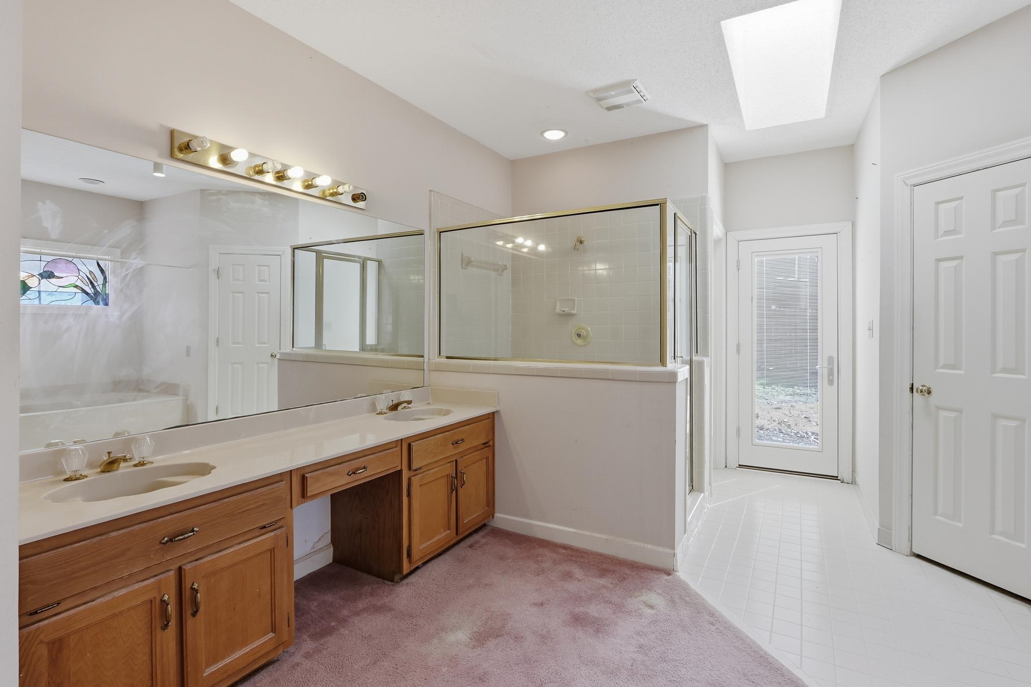 2670 Stout Rd Cove Memphis, TN 38119 - Photo 22 of 37 Bathroom featuring a skylight, a stall shower, double vanity, a bath, and light carpet
