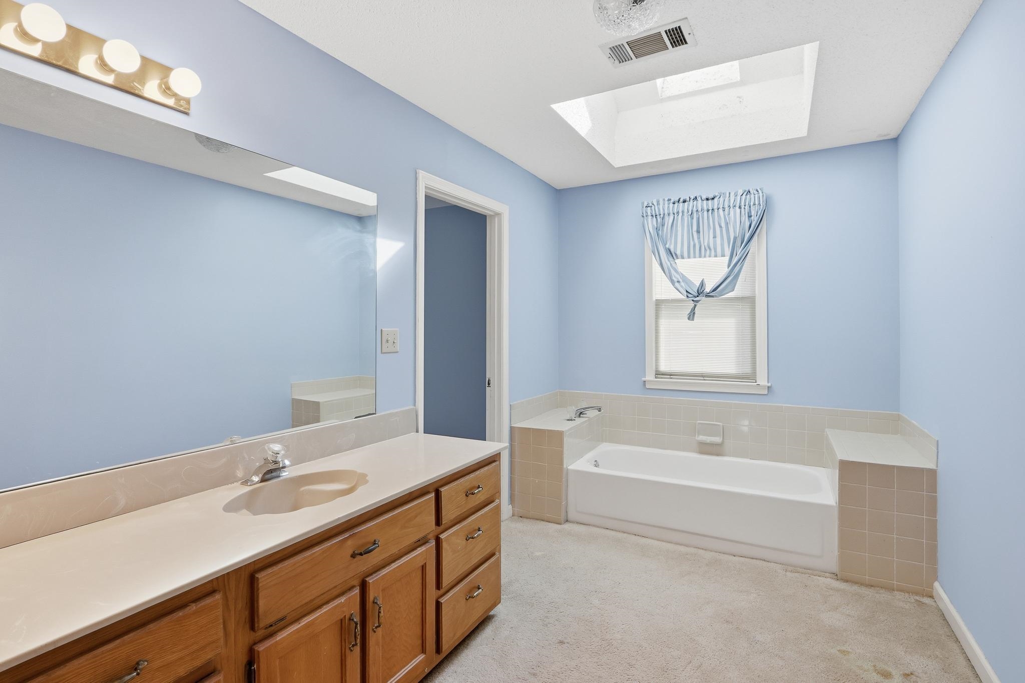 2670 Stout Rd Cove Memphis, TN 38119 - Photo 26 of 37 Bathroom featuring a garden tub, light colored carpet, vanity, and a skylight