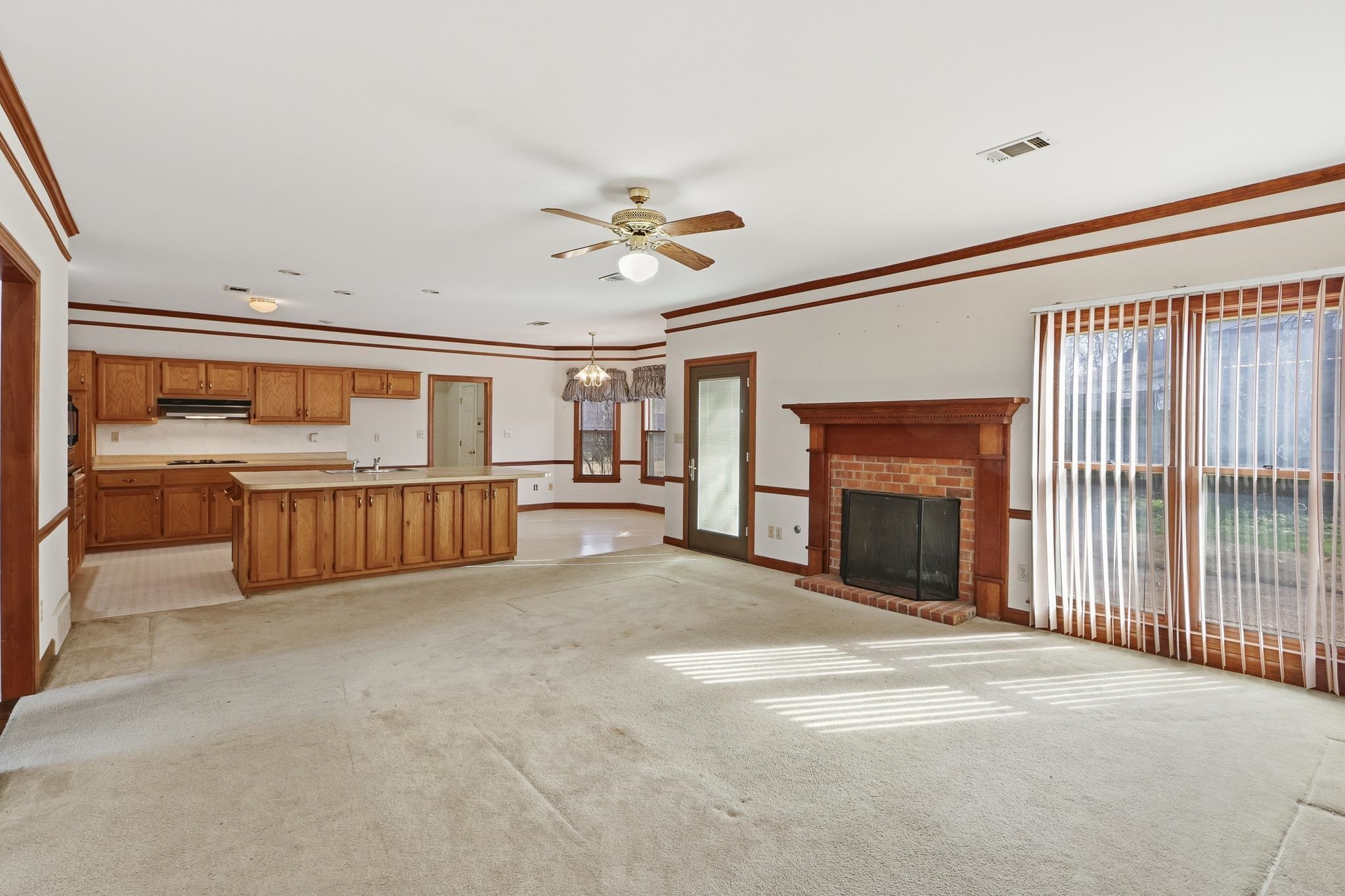 2670 Stout Rd Cove Memphis, TN 38119 - Photo 10 of 37 Unfurnished living room with a fireplace, a chandelier, ceiling fan, light carpet, and crown molding