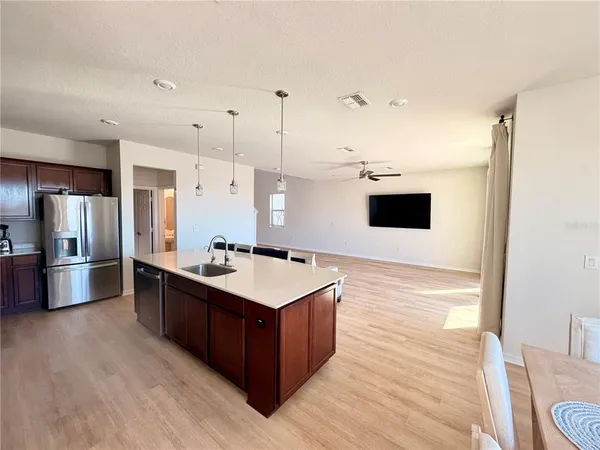 a large kitchen with stainless steel appliances a stove a refrigerator a oven and white cabinets with wooden floor