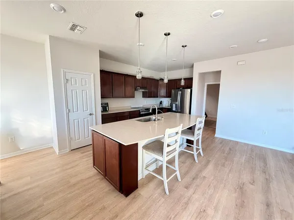 a kitchen with stainless steel appliances a dining table chairs refrigerator and microwave