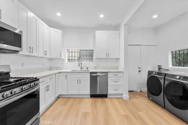 a kitchen with stainless steel appliances granite countertop a stove top oven a sink dishwasher and a microwave oven on the blue kitchen countertops with wooden floor