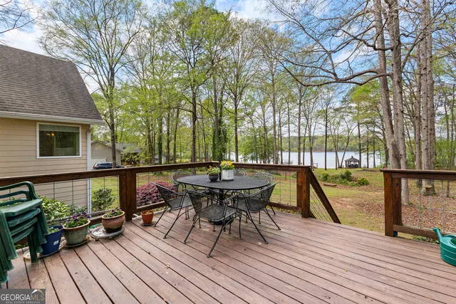 a view of a roof deck with table and chairs a barbeque with wooden floor and fence