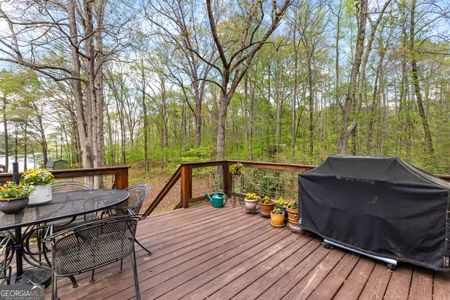 a view of a roof deck with table and chairs a barbeque with wooden floor and fence