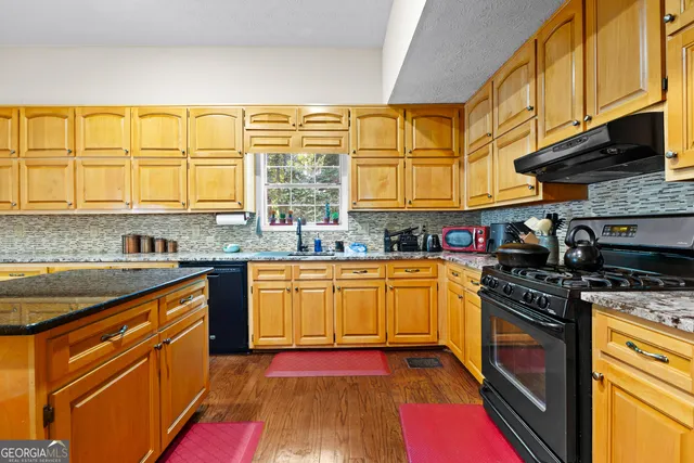 a kitchen with stainless steel appliances granite countertop a stove a sink and a microwave