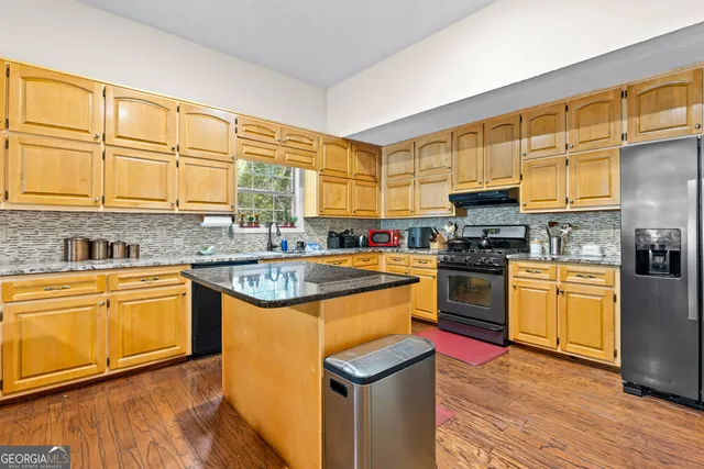 a kitchen with stainless steel appliances granite countertop a stove a sink and a microwave