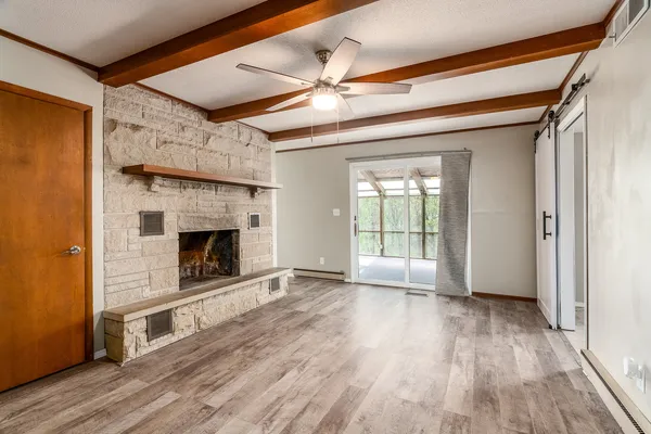 a view of an empty room with wooden floor fireplace and a window