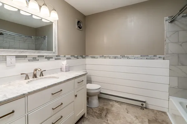 a bathroom with a granite countertop toilet sink and mirror