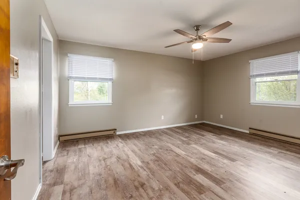 a view of an empty room with wooden floor and a window