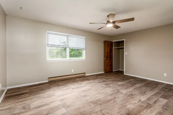 a view of an empty room with wooden floor and a window