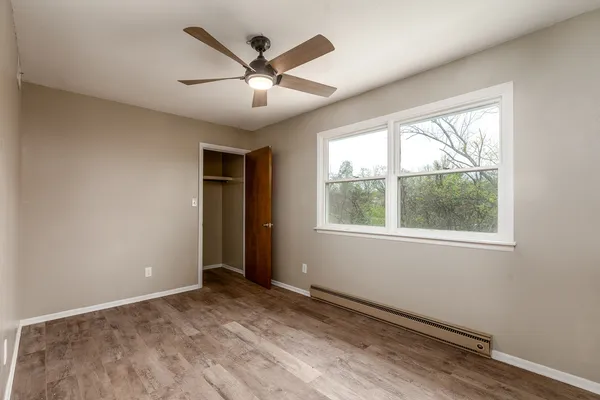 an empty room with wooden floor and windows