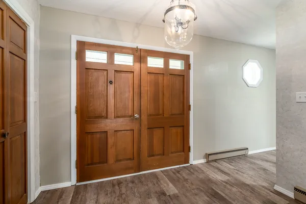 an empty room with wooden floor chandelier fan and windows