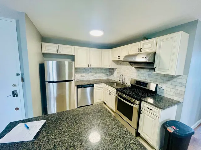 a kitchen with stainless steel appliances granite countertop a refrigerator sink and stove