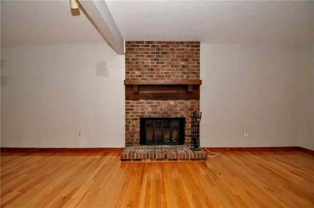 a view of an empty room with wooden floor and a fireplace