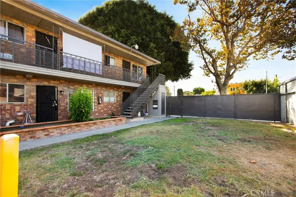 a backyard of a house with table and chairs plants and large tree