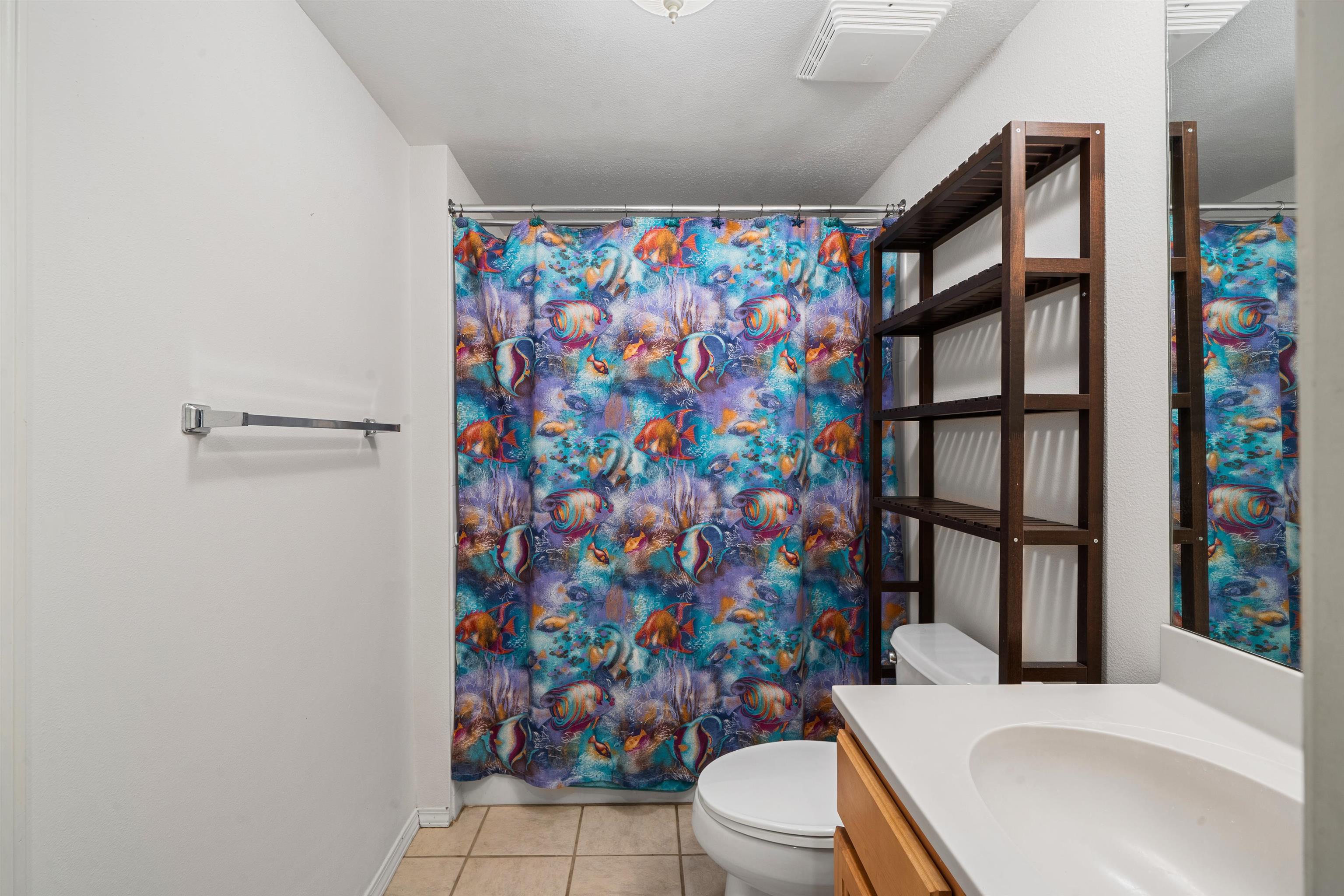 65 Halili Lane, Unit 10F Kihei, HI 96753 - Photo 27 of 48 a white toilet sitting next to a shower curtain