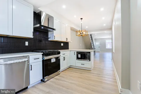 a kitchen with stainless steel appliances kitchen island granite countertop a stove a sink and white cabinets