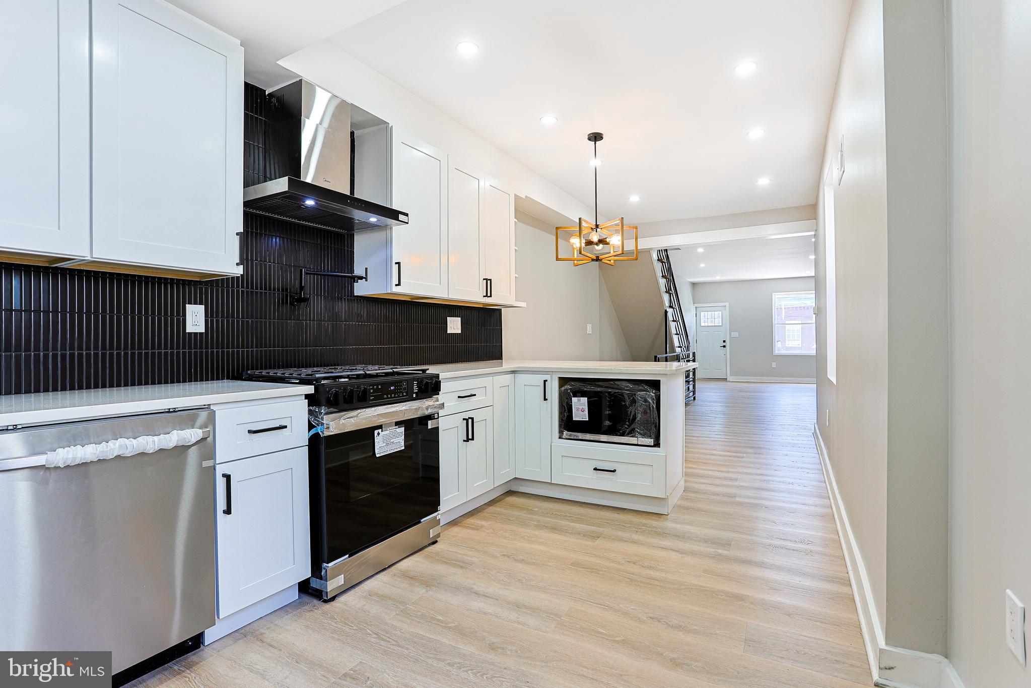 2129 East Tioga Street Philadelphia, PA 19134 - Photo 11 of 32 a kitchen with stainless steel appliances kitchen island granite countertop a stove a sink and white cabinets