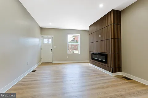 a view of an empty room with wooden floor fireplace and a window
