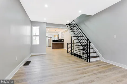 an empty room with wooden floor and staircase