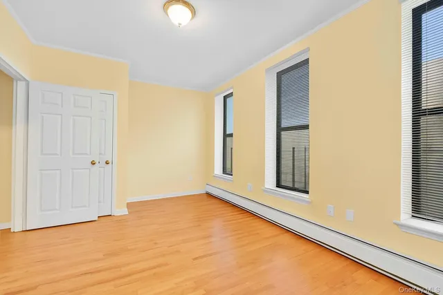 a view of an empty room with window and wooden floor