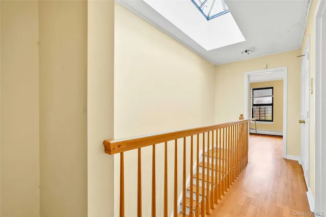 a view of a hallway with wooden floor and a bathroom