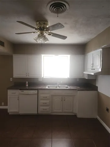 a large kitchen with a sink and dishwasher a stove top oven with wooden floor