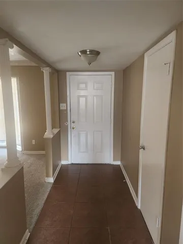a view of a hallway to an empty room with wooden floor and a window
