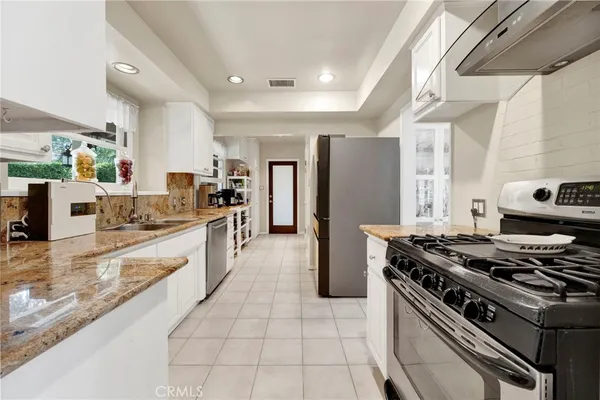 a large kitchen with stainless steel appliances granite countertop a stove and a sink