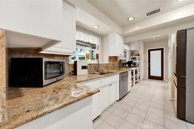a large kitchen with stainless steel appliances kitchen island granite countertop a stove and a sink