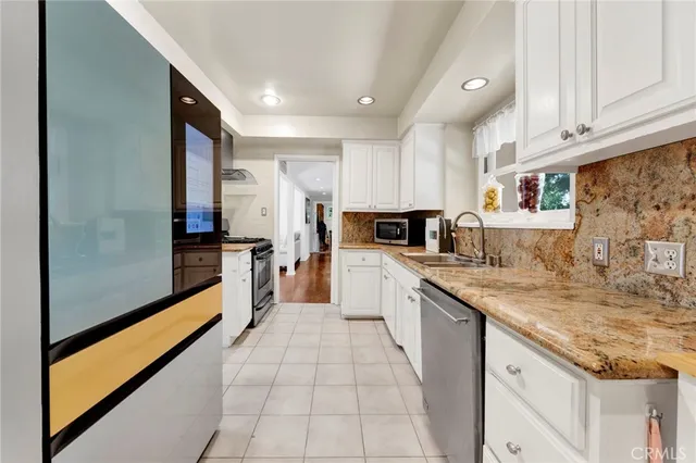 a large kitchen with stainless steel appliances granite countertop a refrigerator and a sink