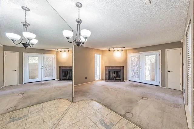 a view of an empty room with a fireplace and a chandelier fan